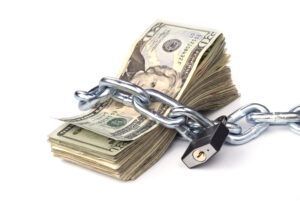 A stack of American paper money wrapped in a chain and locked with a padlock.