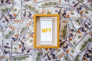 Framed iPhone with "NFT" printed on the screen on top of stacks of money.