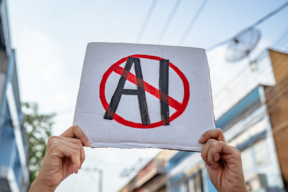 Person holding up a white sign that has "AI" crossed out in protest on the street.