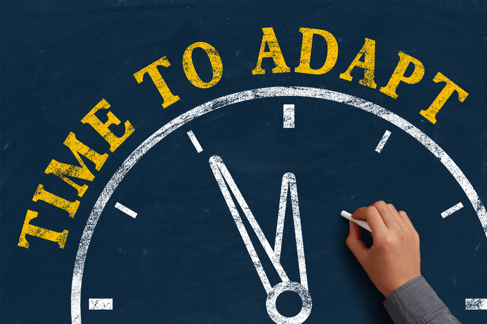 Clock drawn on a chalkboard at 11:55 with the text "Time to Adapt" written above.