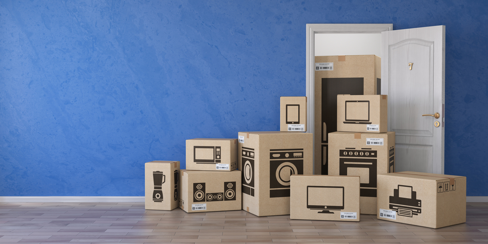 Boxes of electronics stacked in front of an open door on a blue wall.