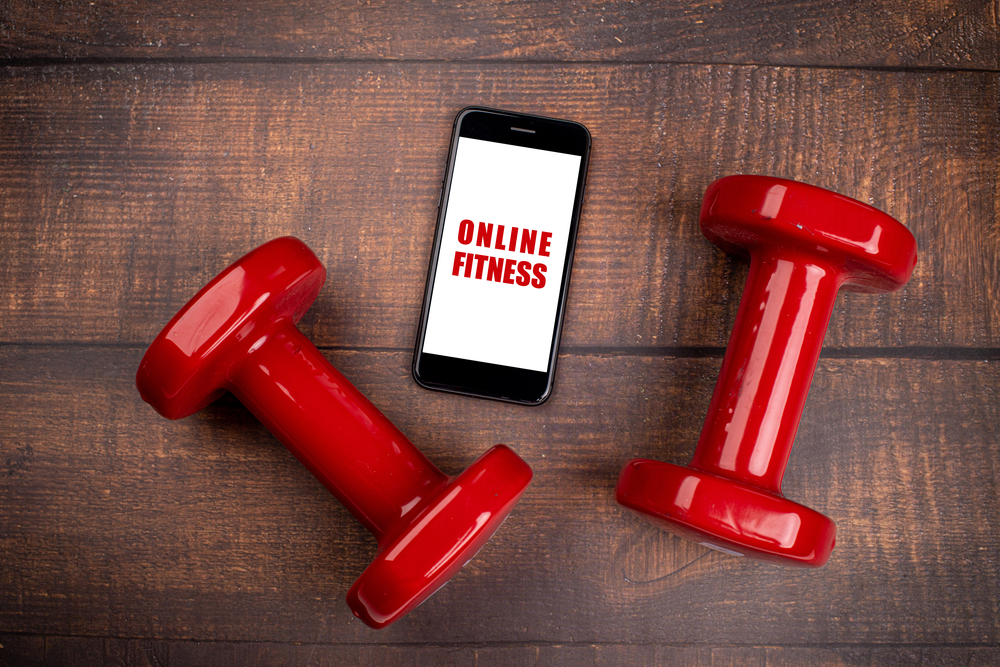 Online fitness coaching app on iPhone with red dumbbell weights