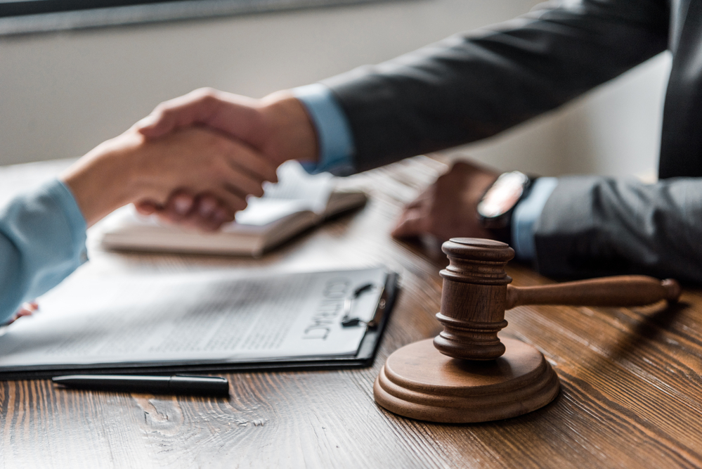 A judge shaking hands with someone behind a gavel.