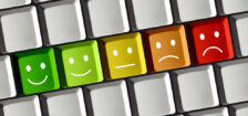 Computer keyboard with a row of keys in the center scaling in color from green to red, with the green having a smiling face and the red having a frowning face.