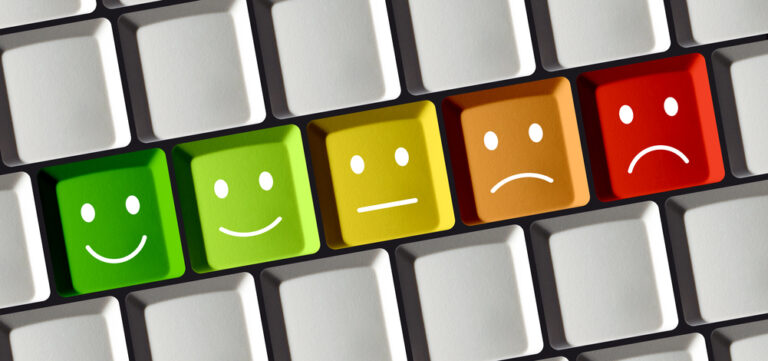 Computer keyboard with a row of keys in the center scaling in color from green to red, with the green having a smiling face and the red having a frowning face.