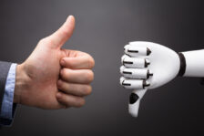 Businessman's hand on the left giving a thumbs up, robot hand on the right giving a thumbs down.