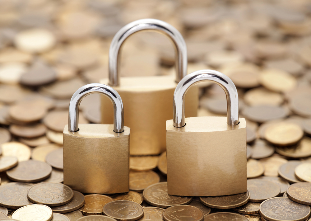 Three locks of varying sizes on top of a bed of coins