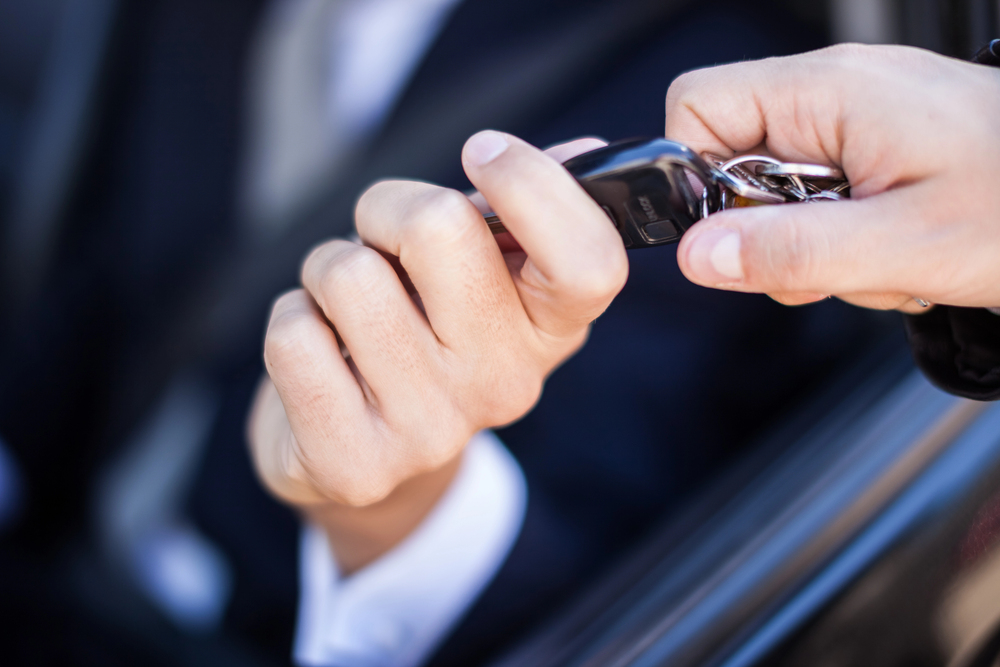 One hand giving car keys to another hand.