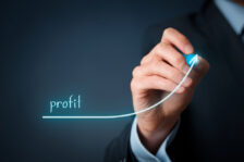 Man's hand drawing a blue line going up with the word "profit"