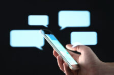 Text messages in cellphone screen with abstract hologram speech bubbles. Instant messaging app. Texting, group chat, sexting or sms concept. Customer service help desk with live support chatbot.