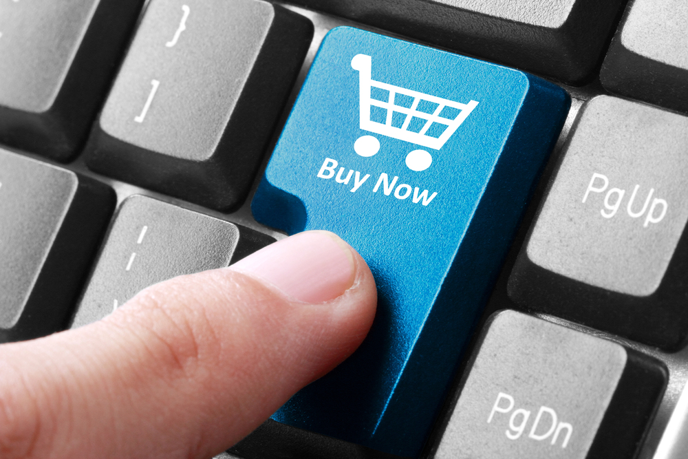 A finger touching a keyboard button with a shopping cart logo and labeled "BUY NOW".