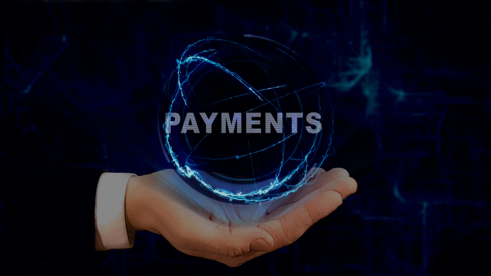 Hand holding a glowing ring of blue dust and the word "PAYMENTS"