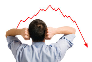 A business man visibly upset looking at a graph that is on decline.