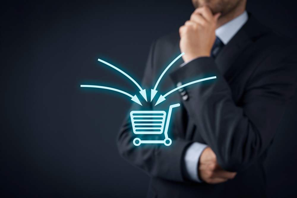 Shopping cart graphic with arrows pointing inside it. A business man wearing a suit stands in the background.