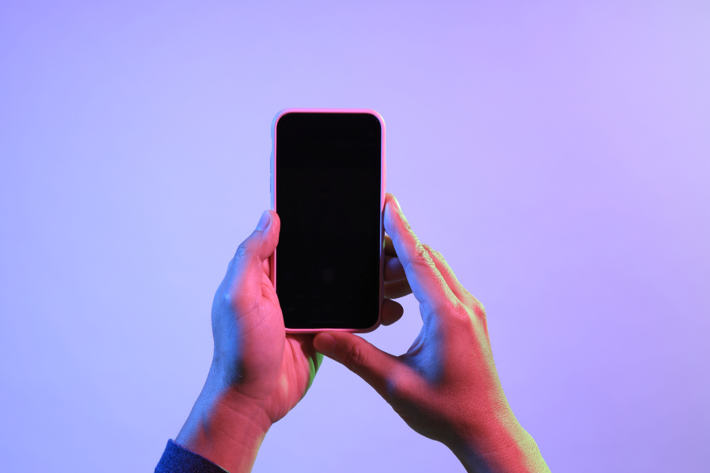 A man's hands holding a smart phone under the vivid color.