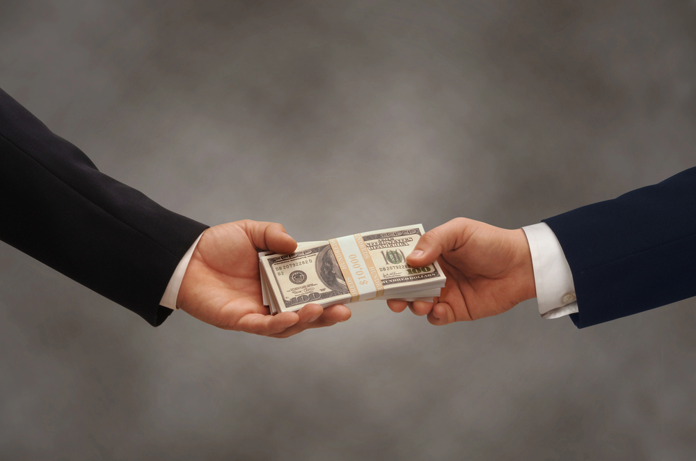 One businessman handing a wad of cash to another businessman