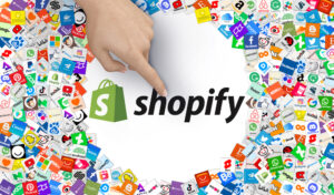 "Shopify" logo in a white circle surrounded by various icons and a finger pointing at it