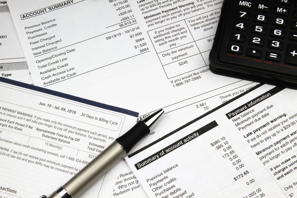 Close-up of files and business papers overlain on top of each other with a pen and calculator
