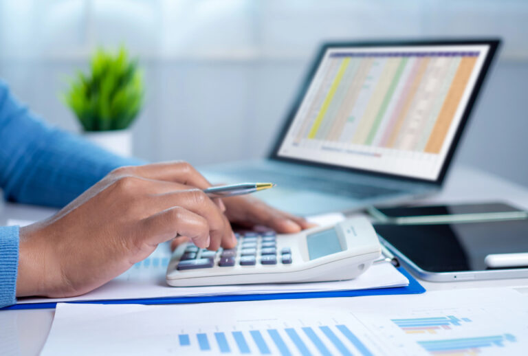 Businesswoman hand working with finances about cost and calculator and laptop with tablet on desk at office in morning light, Business accounting concept, Calculating or checking balance.
