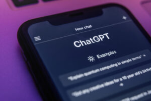 The ChatGPT chatbot on a mobile phone screen in neon light. ChatGPT language model utilizing Open AI's state-of-the-art technology, is accessible through any device.